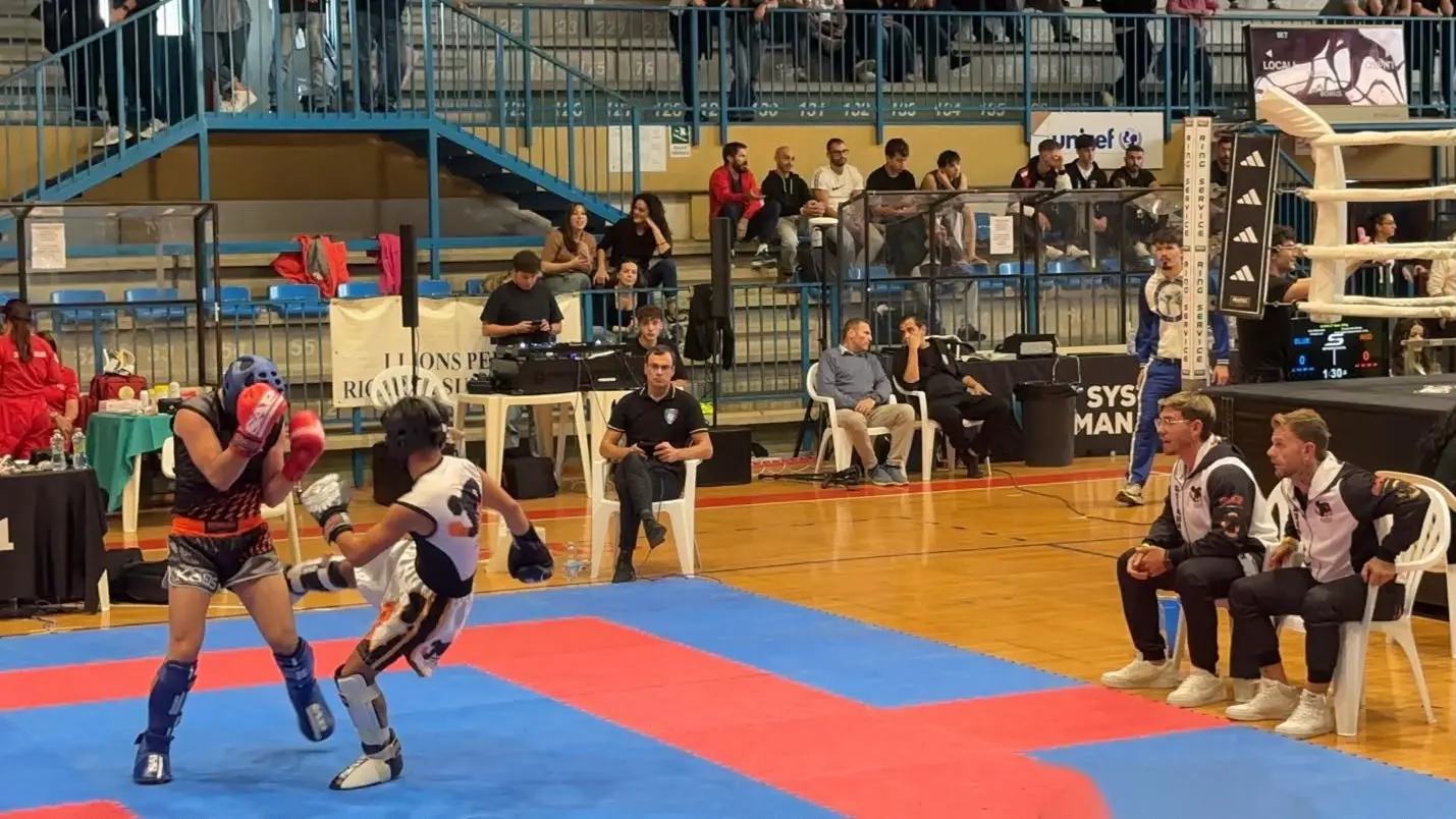 Un atleta del Team Baldassarre durante un match di kickboxing in gara, con i coach a bordo tappeto